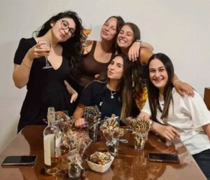 קבוצת נשים מחייכות וחוגגות זמן איכות משותף במהלך סדנת שוקולד בוטיק של עינביז.