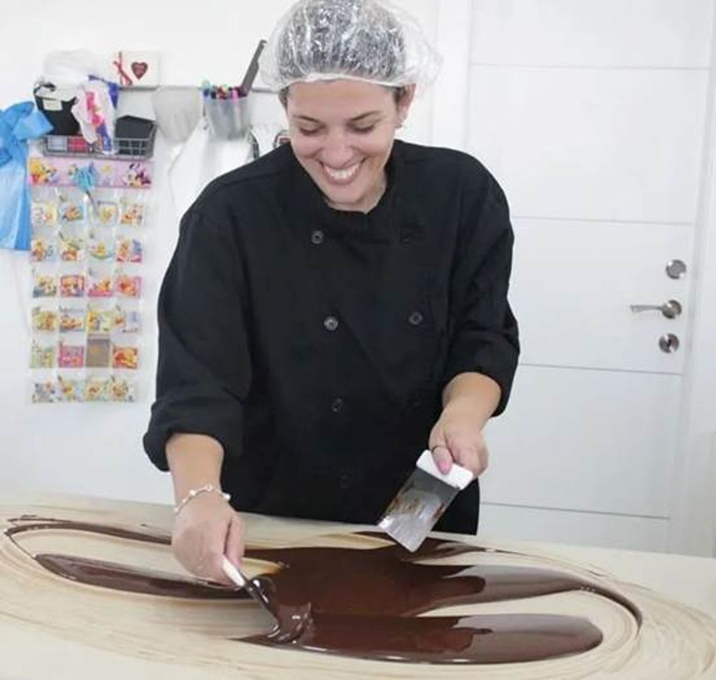 רוני כהנא מעינביז שוקולד מדגימה את טכניקת טמפרור השוקולד על משטח שיש לקבלת ברק ומרקם פרימיום.