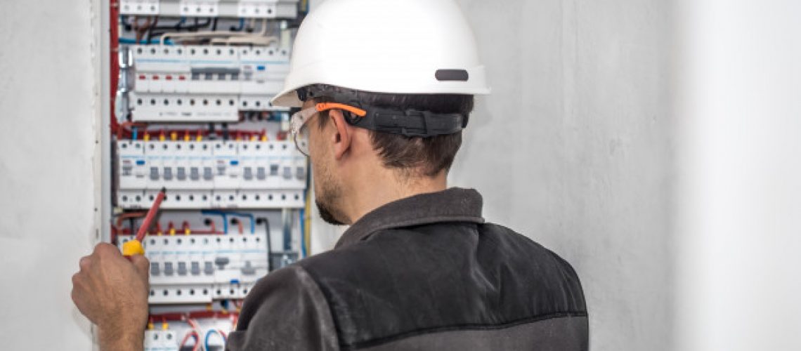 man-electrical-technician-working-switchboard-with-fuses-installation-connection-electrical-equipment_169016-3872